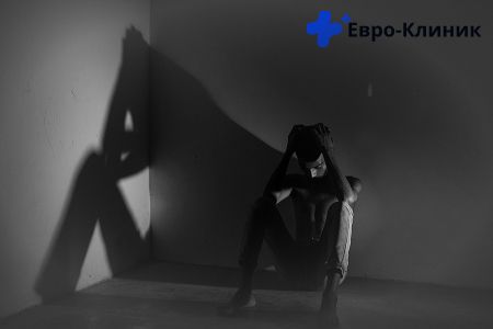 Человек сидит держится за голову в чернобелом цвете