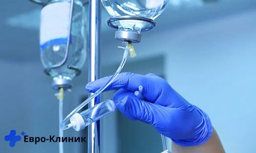 Рука врача в перчатке поправляет пакет капельницы